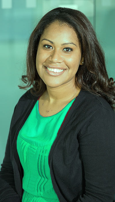 Smiling woman with dark hair wearing a green top and black cardigan.
